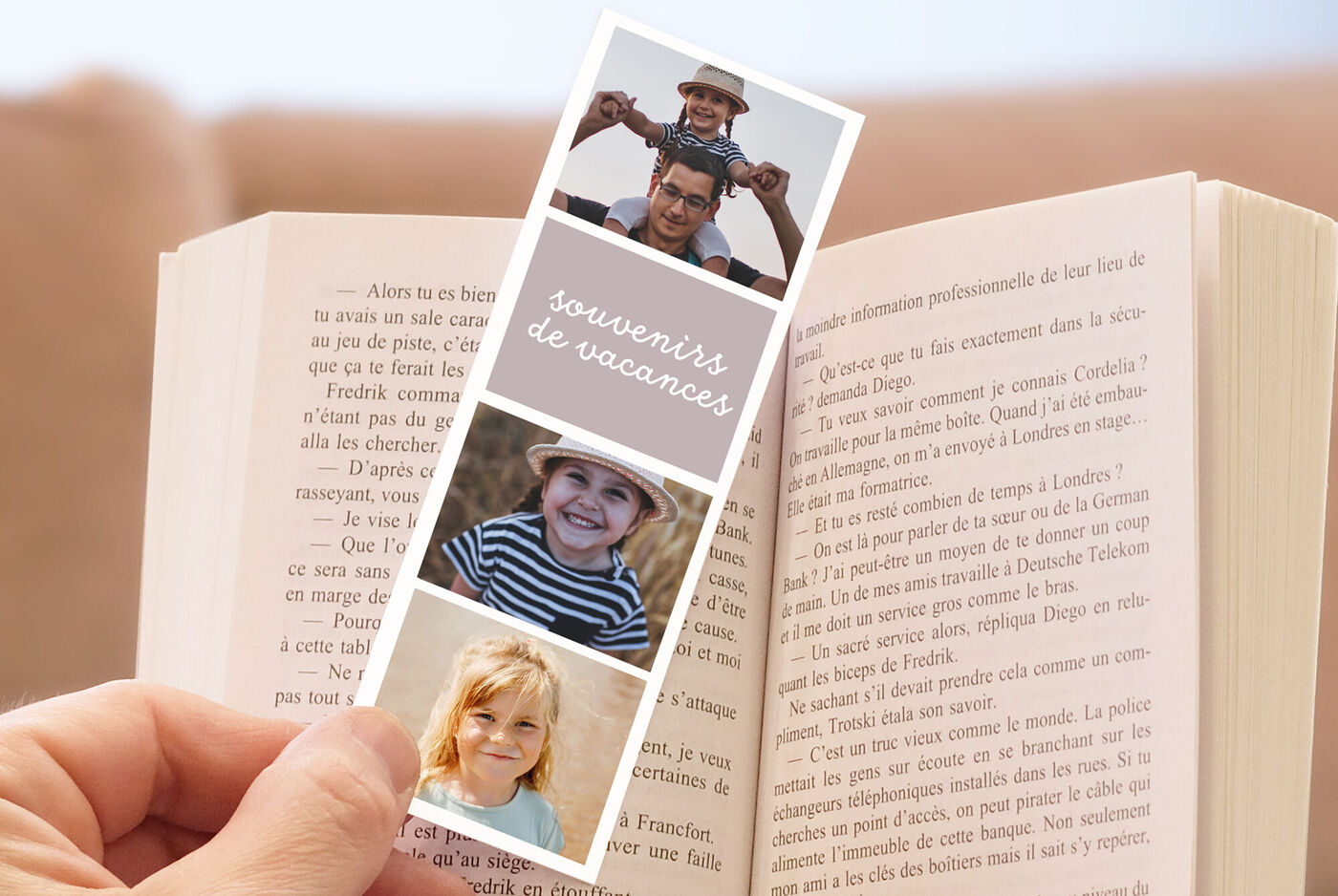 Livre ouvert avec main tenant un marque-pages "souvenirs de vacances" avec 3 photos d'enfants