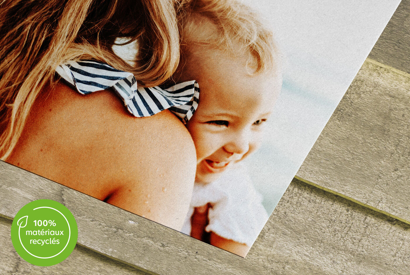 Zoom sur une photo d'un bébé souriant avec pictogramme "100% matériaux recyclés"