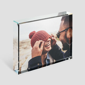 Un couple profite d'un moment chaleureux à la plage. L'homme met un bonnet à la femme.